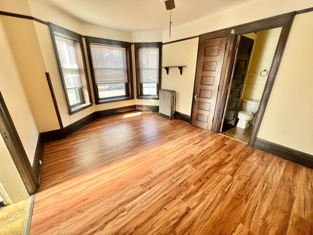 Milwaukee apartments for rent - image - Step into this sunlit space with beautiful wood floors and easy access to a private bathroom, perfect for relaxation.
