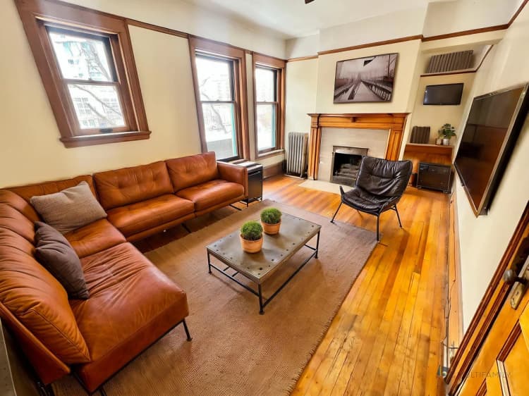 Milwaukee apartments for rent - image - Chic living room featuring a luxurious brown leather sectional, sleek armchair, and a cozy fireplace with contemporary decor.
